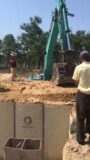 Workers are using a shovel bucket to smooth and compact the sand on the upper layer of the military barrier thumbnail 1